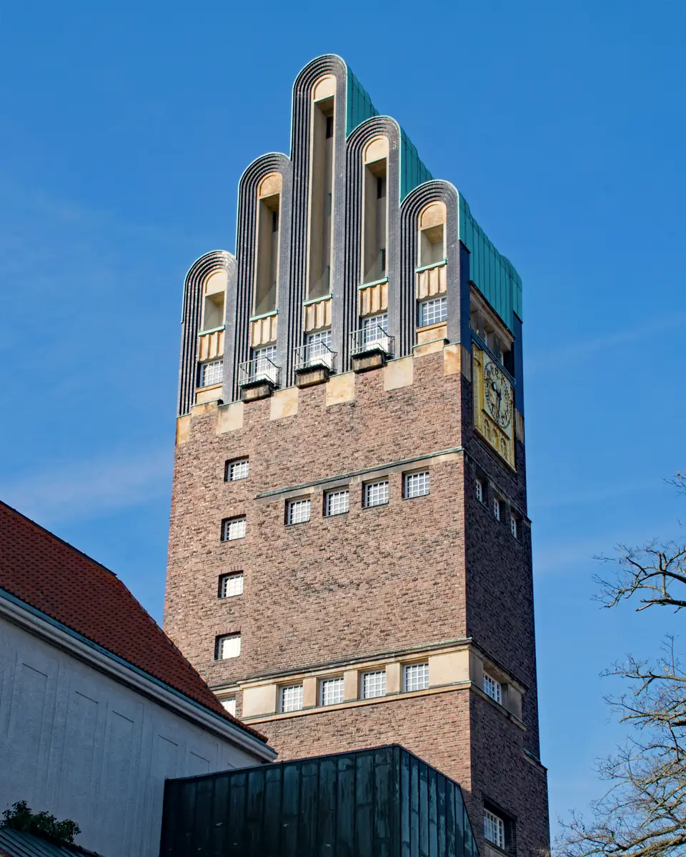 Backsteinturm mit gestaffelten Fensterreihen vor blauem Himmel