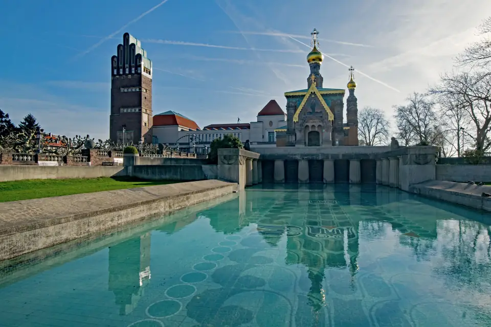Jugendstilbauten über einem langgestreckten Wasserbecken, Aufnahme aus Darmstadt