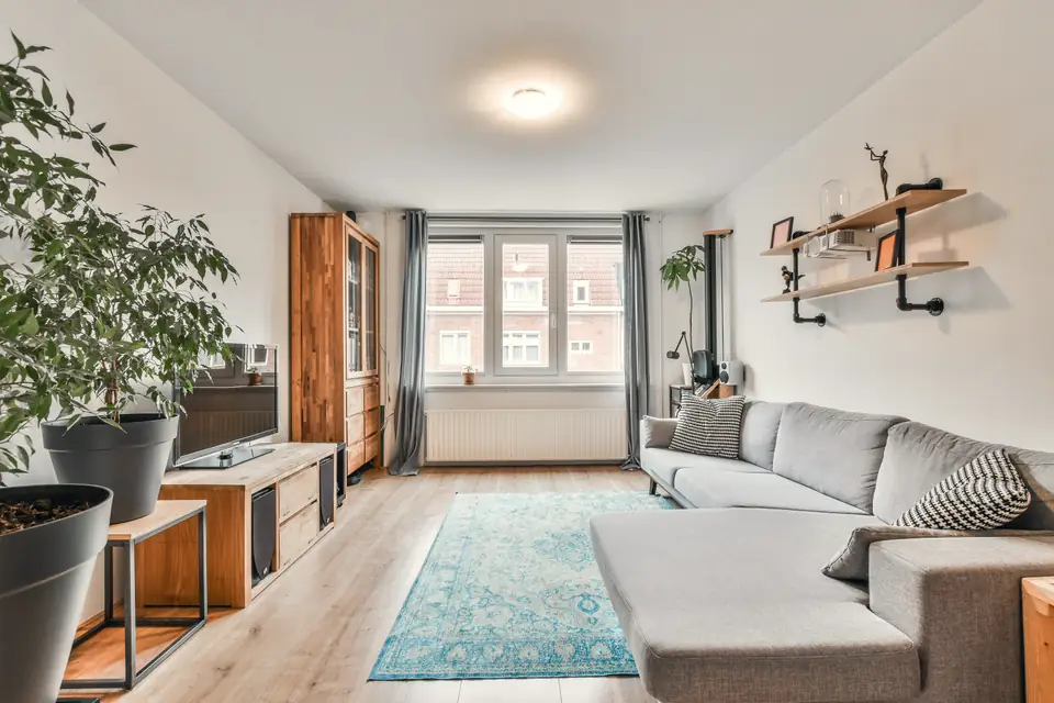 Wohnzimmer einer Etagenwohnung mit Sofa, Teppich und Fenster zur Straße